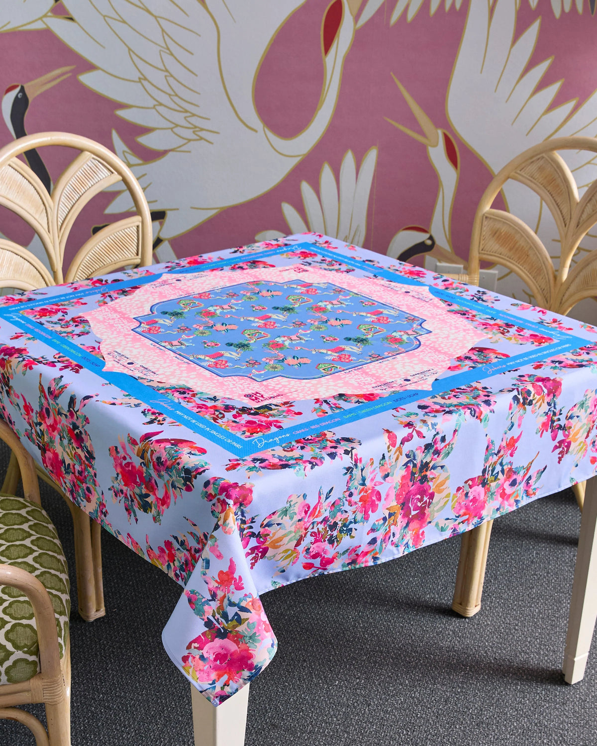 Floral tablecloth on a dining table with a decorative wall in the background