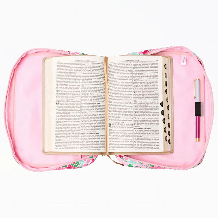 Open book on a pink floral cushion with a pen on a white background
